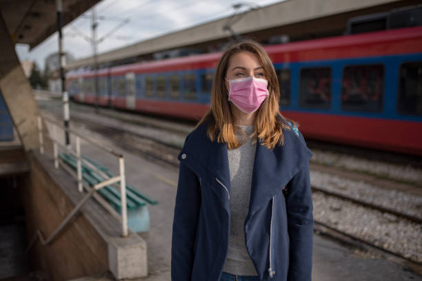 istock Young woman wearing pollution mask waitting for train 1209960047