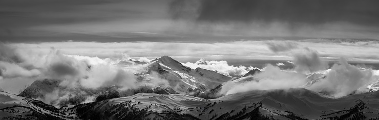 Whistler, British Columbia, Canada. Beautiful Panoramic View of the Canadian Snow Covered Mountain Landscape during a cloudy and vibrant winter sunset. Black and White Art