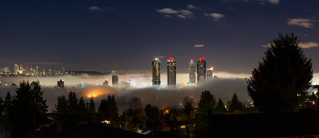 Burnaby, Vancouver, British Columbia, Canada. Beautiful Panoramic Aerial View of a modern city during a fog covered night before winter morning sunrise.