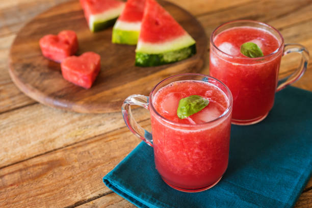 Watermelon pieces and juice in glass cups on table Fresh, cold blended watermelon juice in glass cups on table, close up, no people watermelon juice stock pictures, royalty-free photos & images