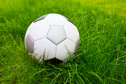 A football ball at the field background of thick green grass, a close-up.