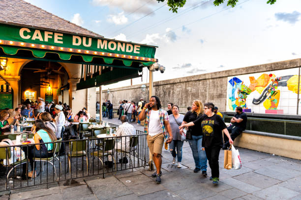 People in line waiting to enter Cafe Du Monde sign for beignet and chicory coffee New Orleans, USA - April 22, 2018: People in line waiting to enter Cafe Du Monde restaurant sign eating beignet powdered sugar donuts and chicory coffee beignet stock pictures, royalty-free photos & images
