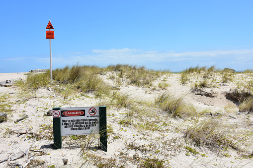 Restricted area sign warning people to keep off sand dunes and warning sign alerting people of unguarded beach.