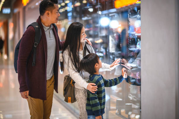 chinese parents and son admiring retail display at mall - harbour city imagens e fotografias de stock