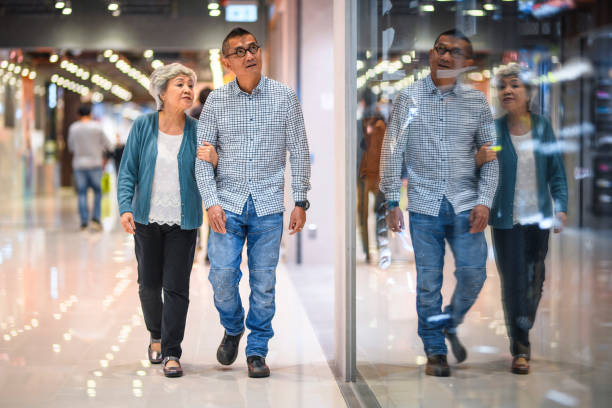 chinese senior shoppers walking arm in arm at mall - harbour city imagens e fotografias de stock