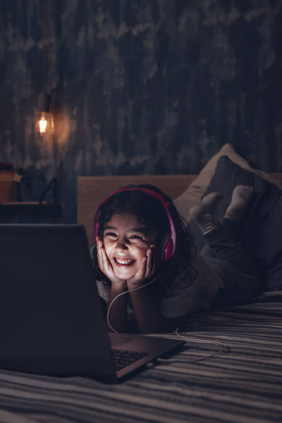 istock happy little girl lying in bed with a computer 1209985761