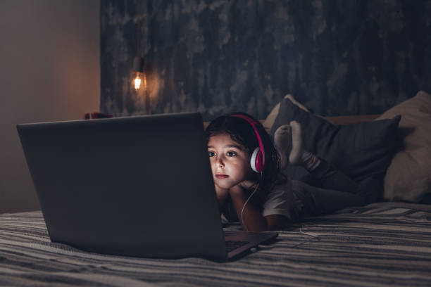 istock little girl lying in bed focused on a computer 1209985764