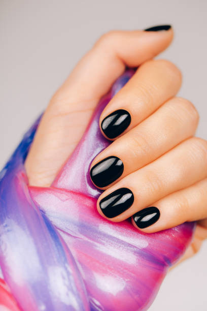 istock hands with black manicure holding slime 1209985814