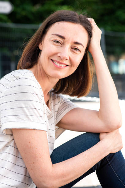 istock beautiful middle aged woman sitting and smiling 1209986267