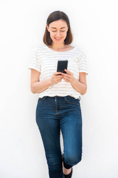 istock older woman holding mobile phone by white background 1209986269