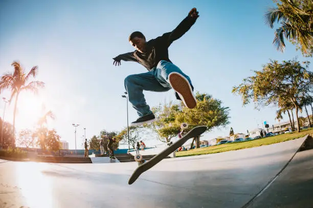 A skateboarder in LA, California rides at a skatepark, attempting an assortment of flip tricks and grinds.  Youth culture and skill in extreme sports.