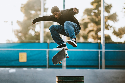 A skateboarder in LA, California rides at a skatepark, attempting an assortment of flip tricks and grinds.  Youth culture and skill in extreme sports.