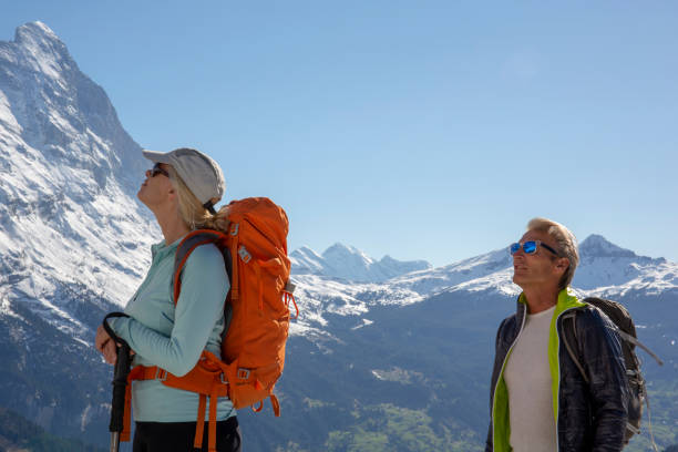 hiking couple ascend alpine slope, in mountains - on top of mountain peak success cold imagens e fotografias de stock