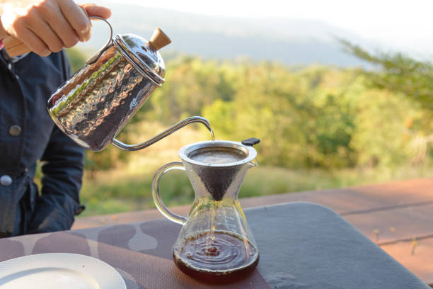 istock Hand drip coffee making pour over coffee with hot water being poured from a kettle with mountain view and natural green view feeling chill and relax in nature 1210000213