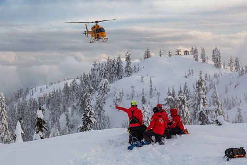 North Vancouver, British Columbia, Canada - Feb 17, 2020: North Shore Search and Rescue are rescuing a man skier with a broken leg in the backcountry of Seymour Mountain with a helicopter in winter.