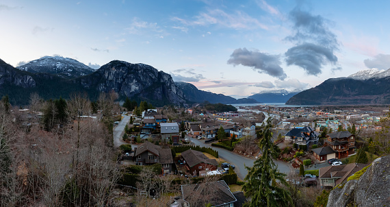 Squamish, British Columbia, Canada. Aerial View of a small Outdoor town surounded by Canadian Mountains during a vibrant and colorful winter sunrise. Panorama