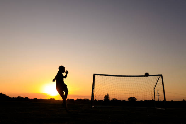 мальчик практикующих футбольные навыки на закате - goalie soccer soccer player teenage boys стоковые фото и изображения