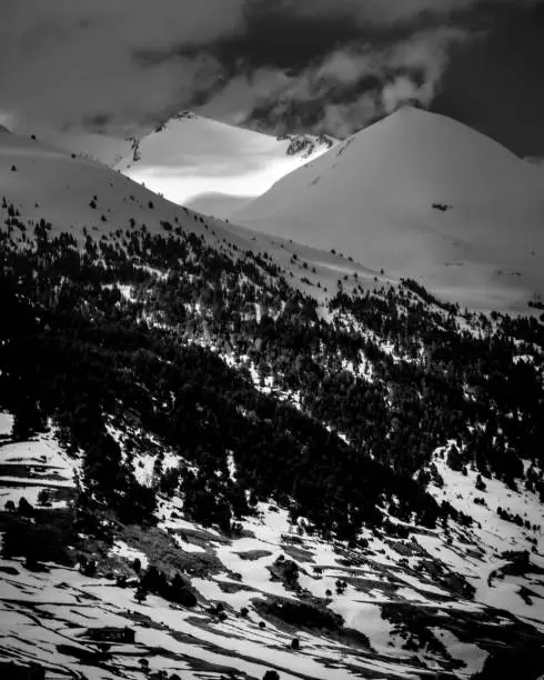 Vertical snow mountains of Andorra in black and white with clouds on winter season