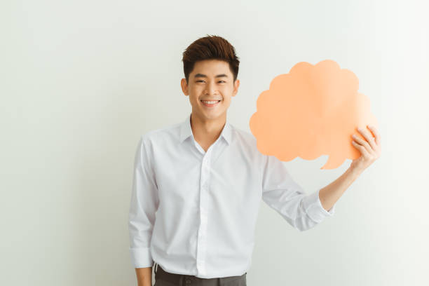 istock Portrait of young Asian man holding empty speech bubble over white background. 1210016105