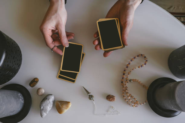 stack of fortune telling cards and a woman's hands on a white table