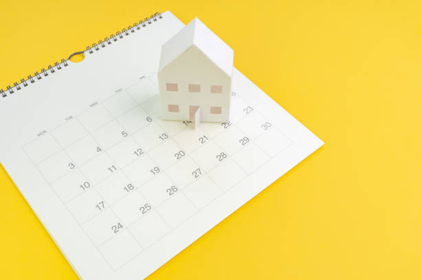 Day to pay for mortgage, buying new house planning or real estate and property reminder concept, paper craft house on white calendar with yellow background stock photo