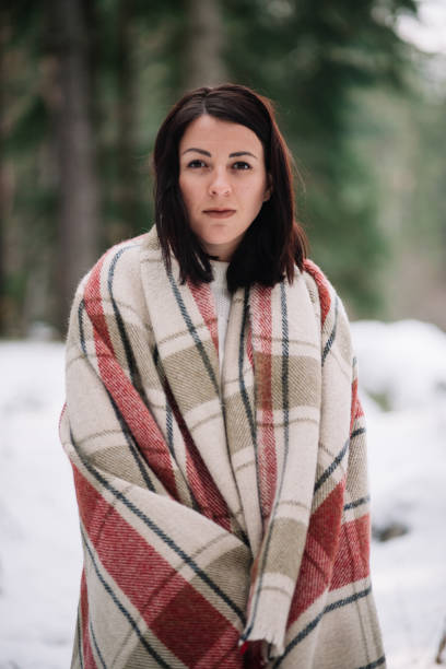 istock Beautiful woman covered with blanket in snowy forest 1210023879