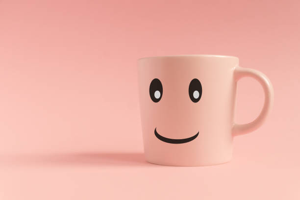 istock Pink cup on pink background. Smiling face on a mug. Minimal creative concept 1210024669
