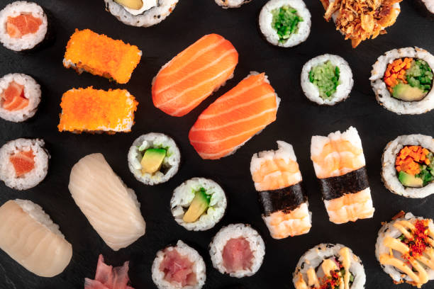 duży zestaw sushi, nakręcony od góry na czarnym tle. płaski leżał różnych maki, nigiri i rolkach - sushi california roll salmon sashimi zdjęcia i obrazy z banku zdjęć