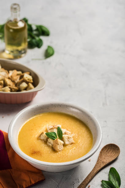 istock Pumpkin and carrot soup with cream and spinach with crackers on a white background. 1210027101