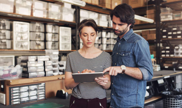 What every successful office runs on, technology Shot of a businessman and businesswoman using a digital tablet in a creative office warehouse office stock pictures, royalty-free photos & images