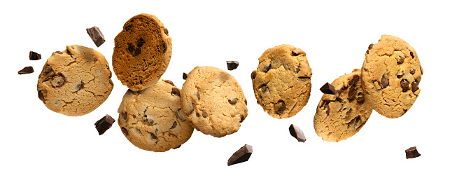 Chocolate chip cookies with pieces of chocolate flying or falling over white background