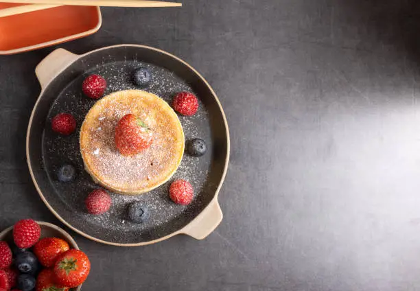 Homemade japanese hotcakes on a wooden background with raspberries, blackberries and strawberries and sugar powder.Top view.