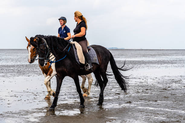Cuxhaven, Germany - August 6 2019: Two unidentified women riding on Cuxhaven beach at low tide
