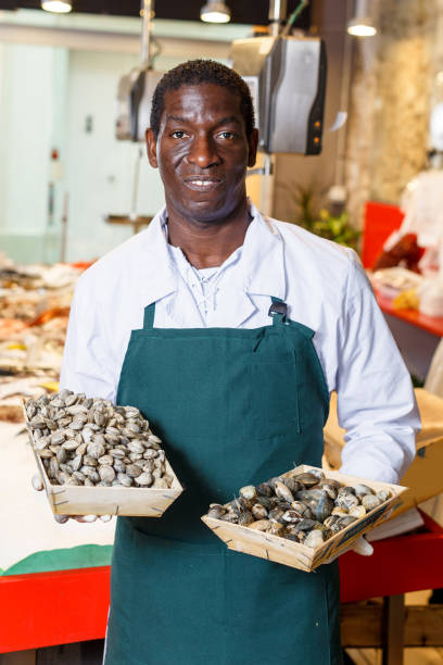istock Salesman offering fresh clams in fish store 1210031804