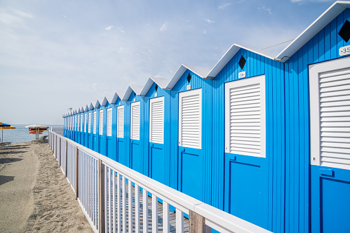 Traditional Italian beach huts on a bright sunny day,Blue beach cabins arranged in rows up on the seashore,Varazze Liguria Italy.
