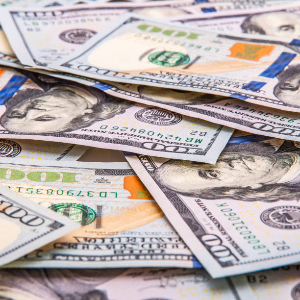 istock The background of scattered hundred dollar bills. 1210034346