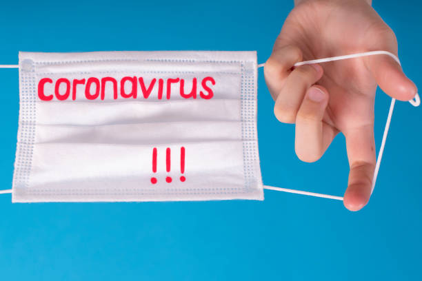 istock Hands on a blue background with a protective mask with the text Coronavirus. Chinese outbreak of coronavirus.Coronovirus Quarantine Concept. 1210037370