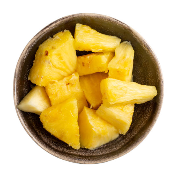 istock Chopped ripe pineapple in ceramic bowl isolated on white background. Top view. 1210038635