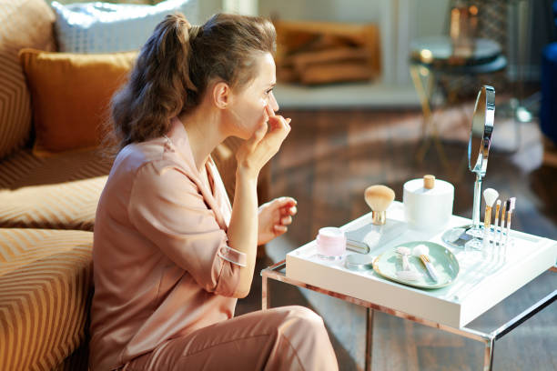 istock stylish woman applying cream and looking in mirror 1210038899