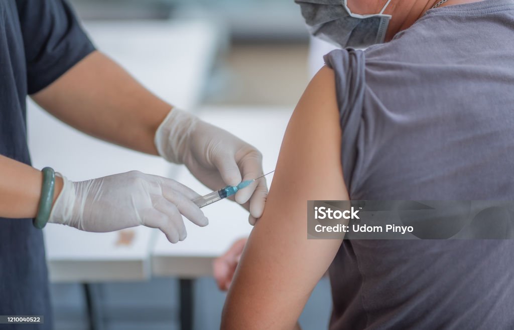 Injections in the arm to treat the disease. The doctor is injecting male patients.In the medical's hand have syringes. Vaccination Stock Photo