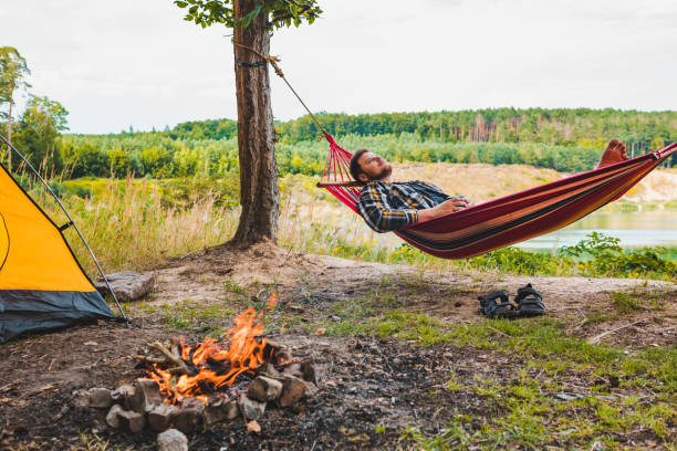 istock man laying on hammock at lake beach near camp fire 1210041320