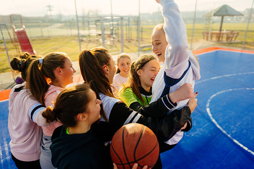 Photo of smiling teenage girls on a basketball court celebrating after the great match