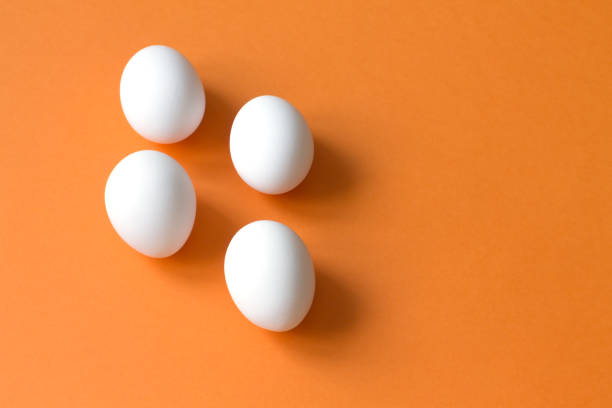 istock Four white eggs lie on a colorful terracotta background. 1210044993