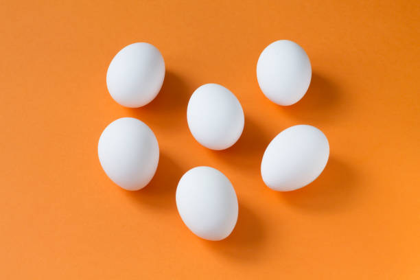 istock Six white eggs in the center of a bright terracotta background. 1210044996