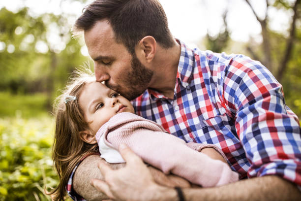 istock Affectionate single father kissing his small daughter in nature. 1210045673