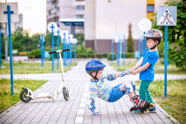 istock two boys in park, help boy with roller skates to stand up 1210045830