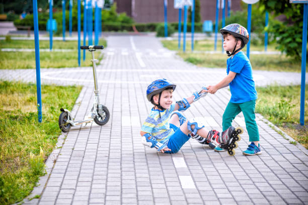 istock two boys in park, help boy with roller skates to stand up 1210045840