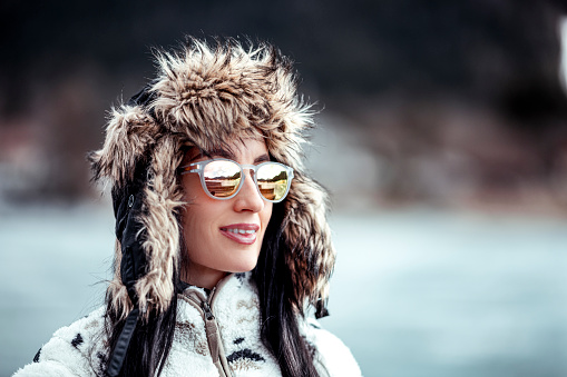 A woman with an ear flap hat and sporty sunglasses.