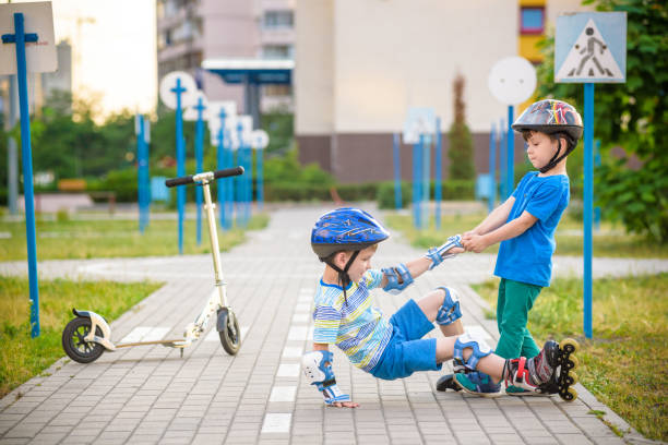 istock two boys in park, help boy with roller skates to stand up 1210045989