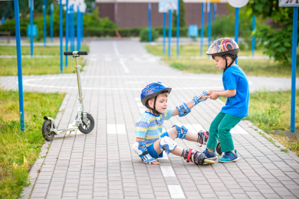 istock two boys in park, help boy with roller skates to stand up 1210045995